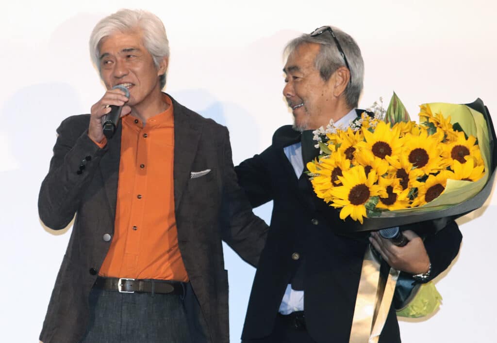佐藤浩市から花束を贈られ笑顔の寺尾聰 ©︎The Hollywood Reporter Japan