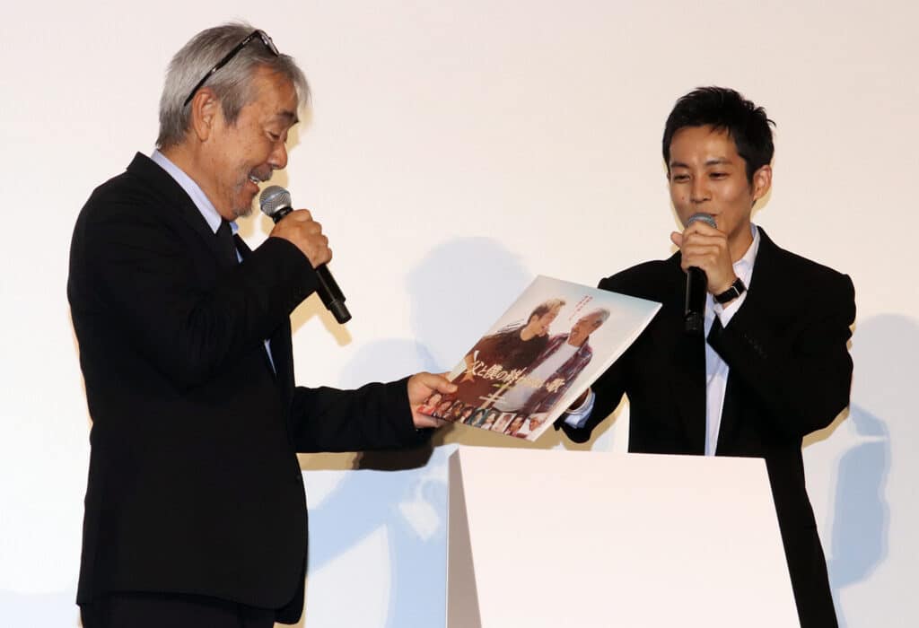 松坂桃李らか贈られたレコードを見つめる寺尾  ©︎The Hollywood Reporter Japan