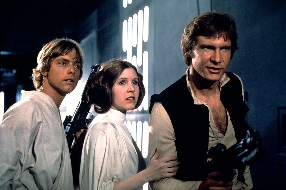 『スター・ウォーズ エピソード4／新たなる希望』に登場するルーク・スカイウォーカー役のマーク・ハミル、レイア姫役のキャリー・フィッシャー、ハン・ソロ役のハリソン・フォード Courtesy of Everett Collection